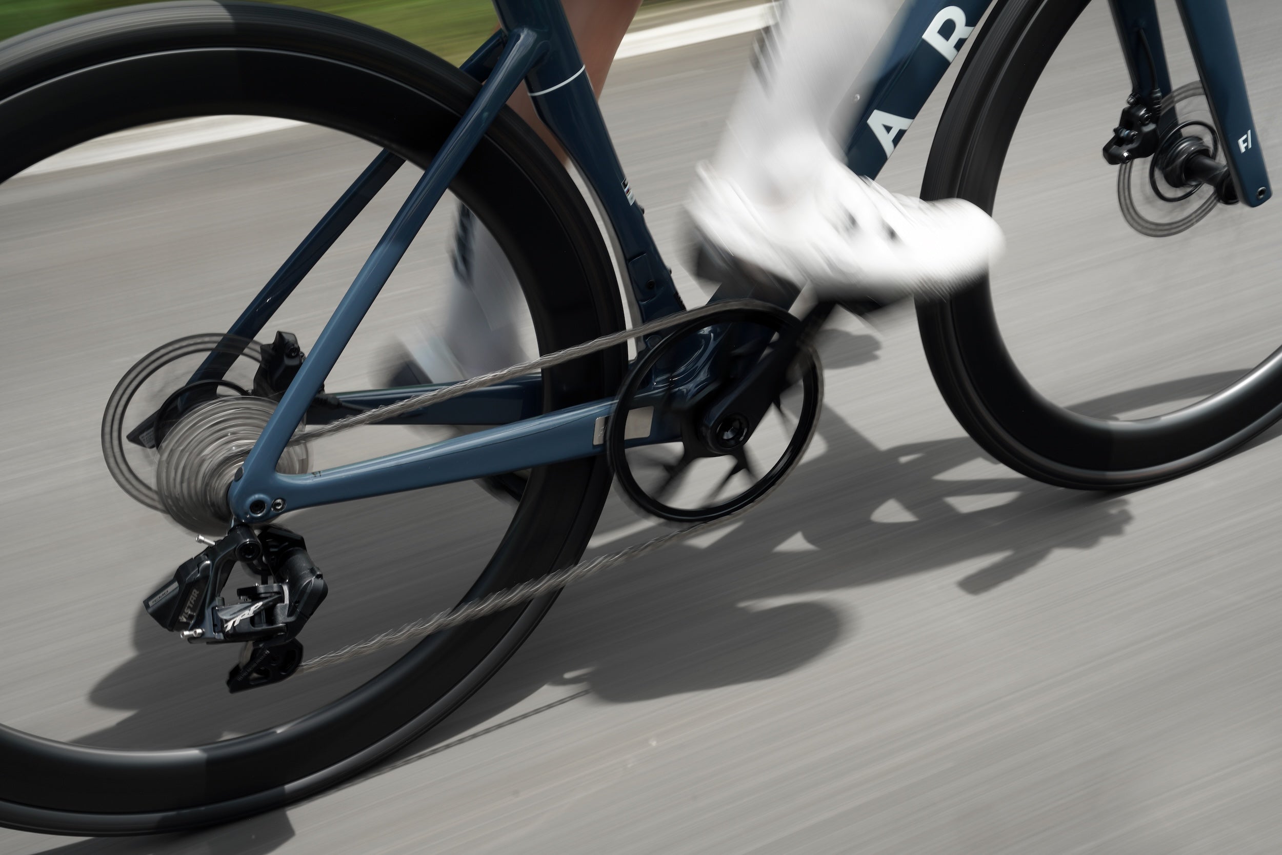 Close-up of a bicycle with the TRP VISTAR and a person wearing white shoes on a road.