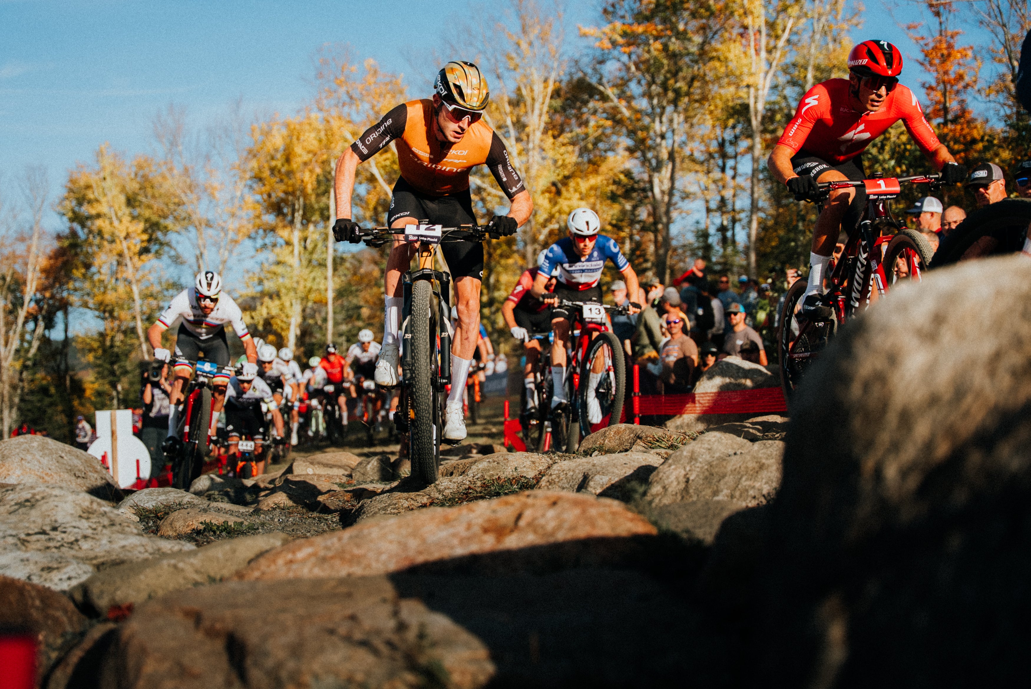 Bicycle race on a rocky trail at Lake Placid with riders and spectators.