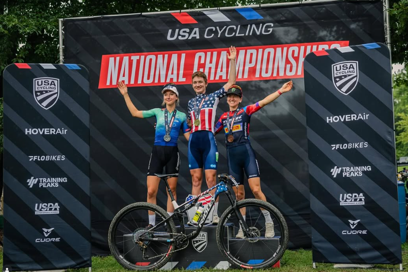 Three cyclists celebrating on a podium at 'USA Cycling National Championships' 