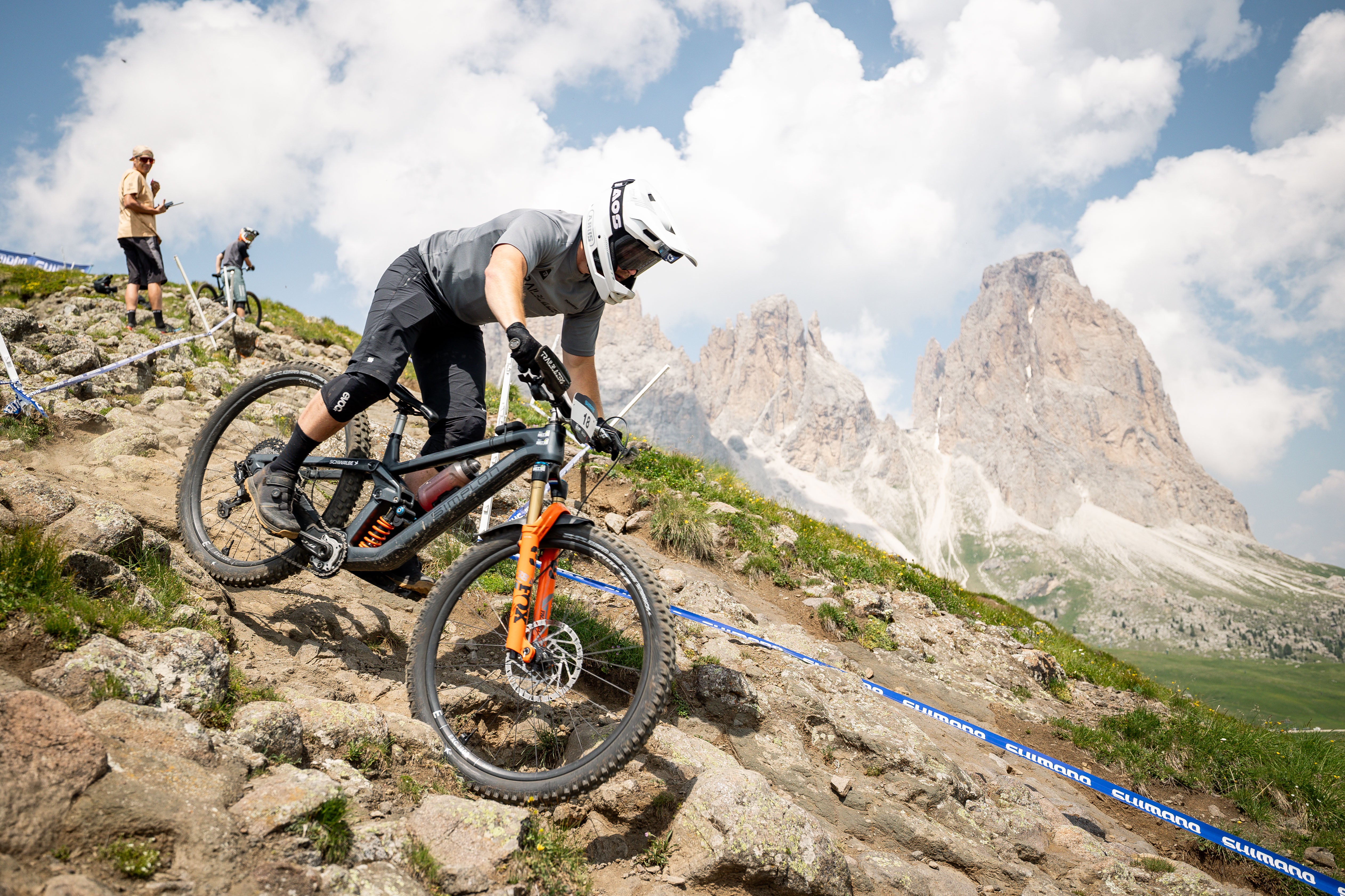TRP Athlete riding a mountain bike on a rocky trail with Three Peaks of Val di Fassa  in the background