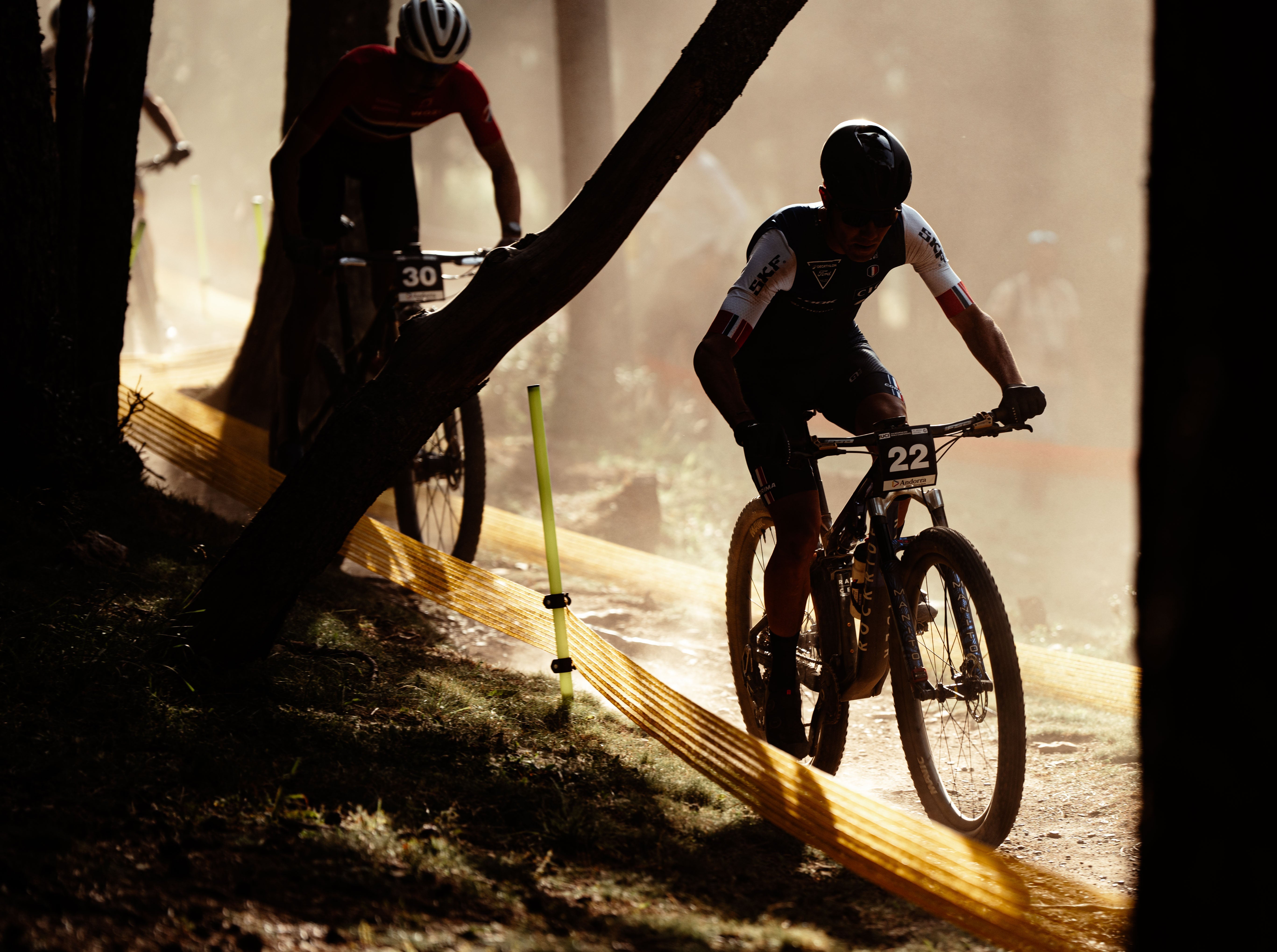 2 men riding downhill bikes in sunset