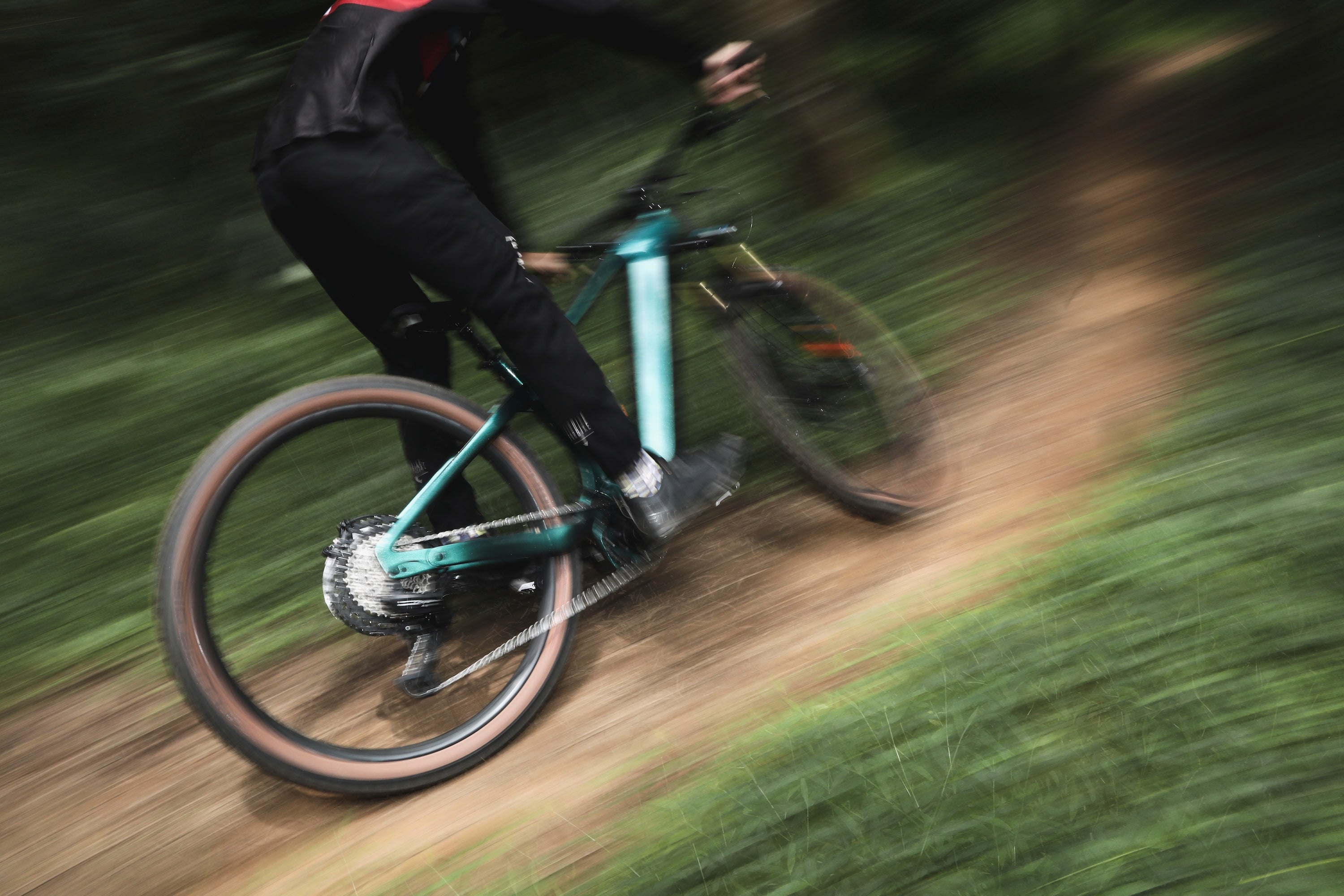 Person riding a mountain bike with EASIA12 drivetrain group on a trail with motion blur effect